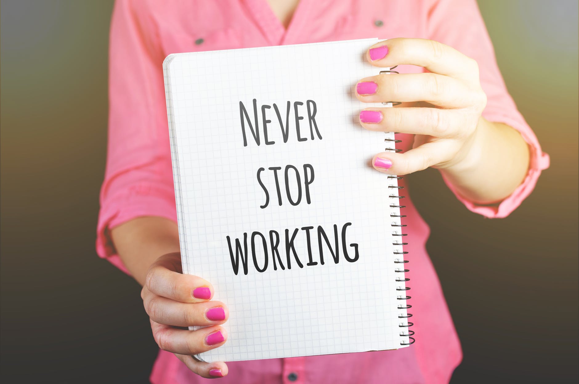 woman holding never stop working print notebook
